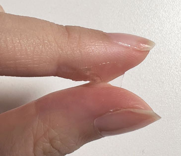 Close-up of two fingers with regular jelly tabs on a plain background