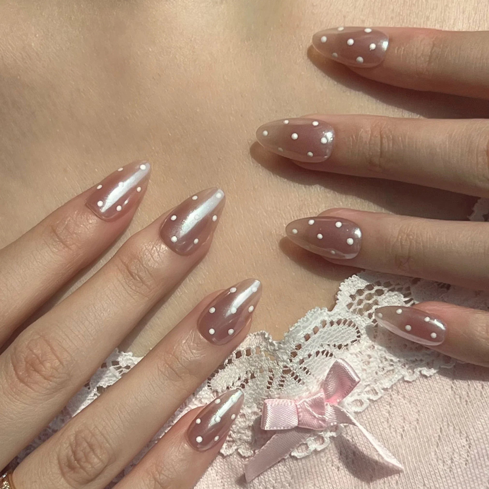 Nails with a polka dot design on a lace background. Press on nails on-hand display. LuxeCharm