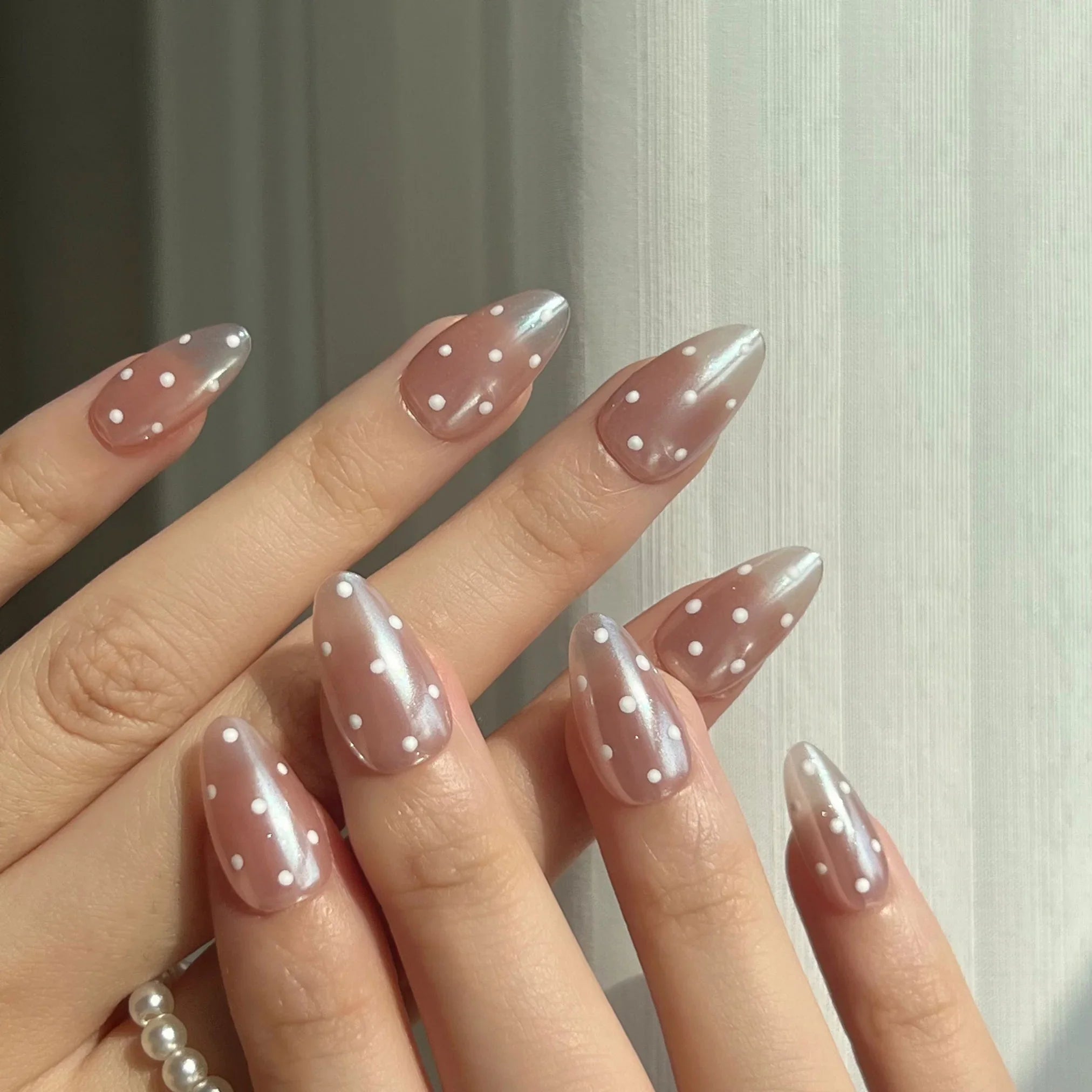 Nails with pink polish and white polka dots on a neutral background. LuxeCharm Press on nails