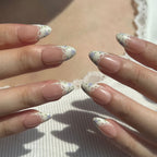 Close-up of hands with floral nail design on a neutral background. Set of purple coquette nail art designs with hand-painted purple floral patterns. LuxeCharm press on nails
