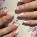 Close-up of hands with floral nail design on a floral background. Set of coquette nail art designs with hand-painted pink floral patterns