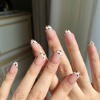 LuxeCharm Quiet Prairie nails on hand with short oval shape and minimal cow-print detailing