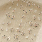 Translucent sheet with floral and ribbon designs on a beige background. LuxeCharm nail stickers