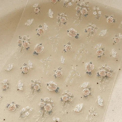 Translucent sheet with floral and ribbon designs on a beige background. LuxeCharm nail stickers