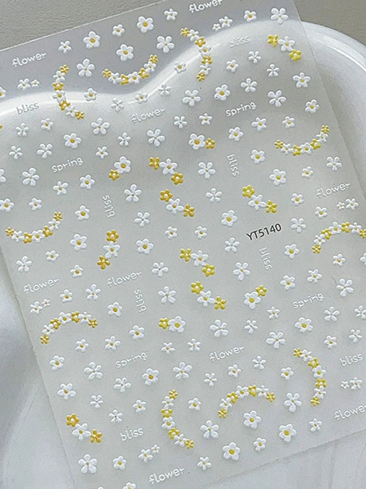 Sheet of white and yellow floral nail art stickers on a clear background. LuxeCharm nail stickers