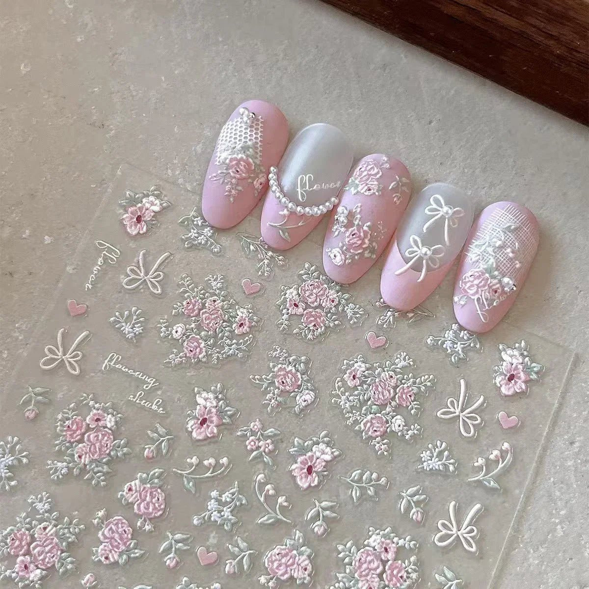 Nail art stickers with floral and bow designs on a clear sheet. LuxeCharm nail stickers
