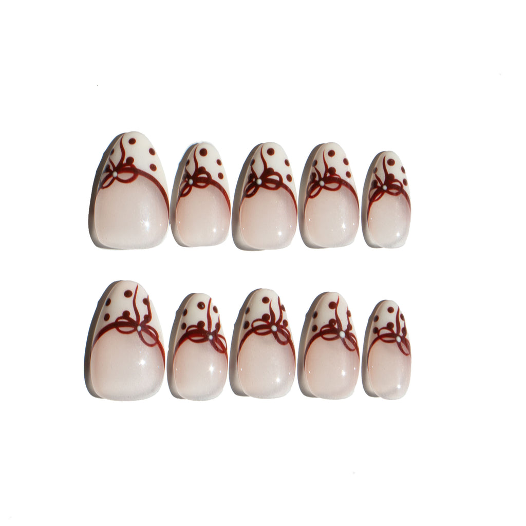 Set of LuxeCharm press on nails with red bow and polka dot designs on a white background. Ten LuxeCharm press on nails