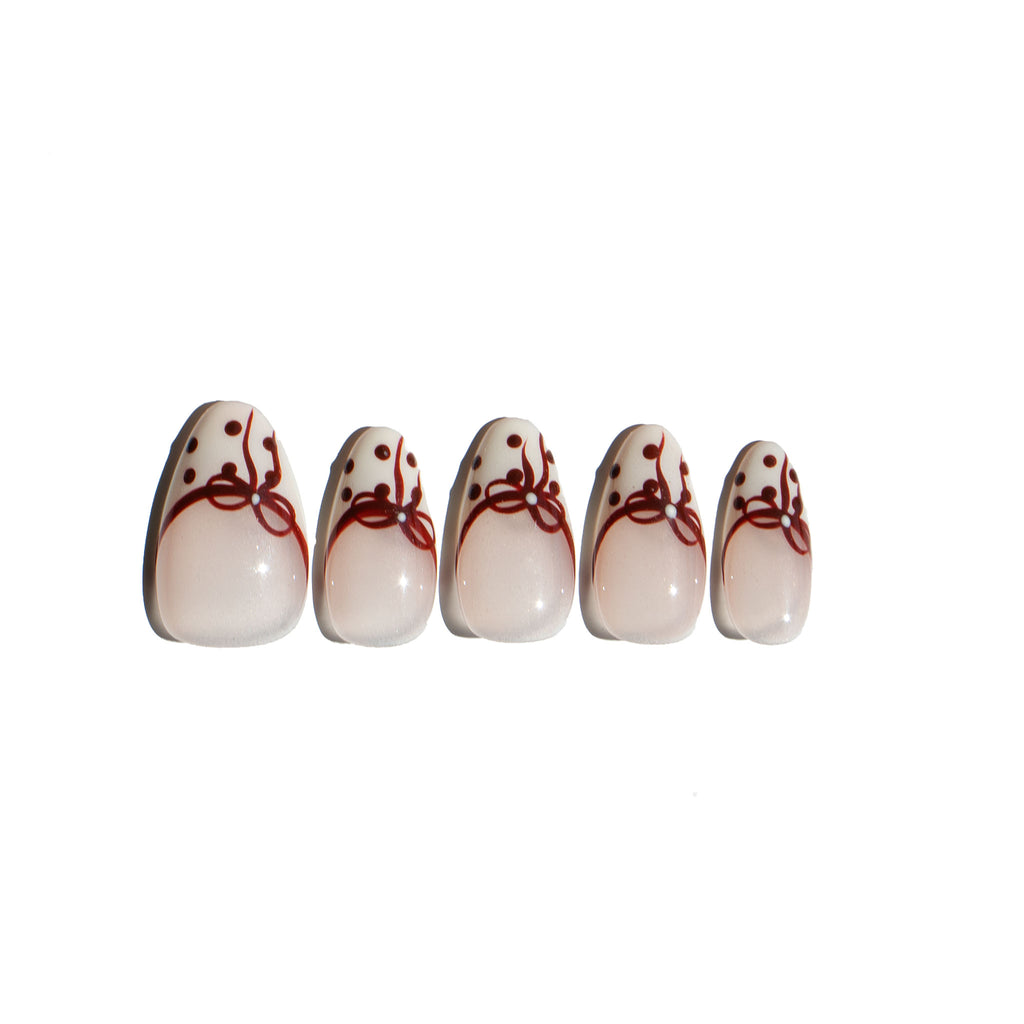 Five press on nails with red bow and polka dot design on a white background. LuxeCharm fake nails
