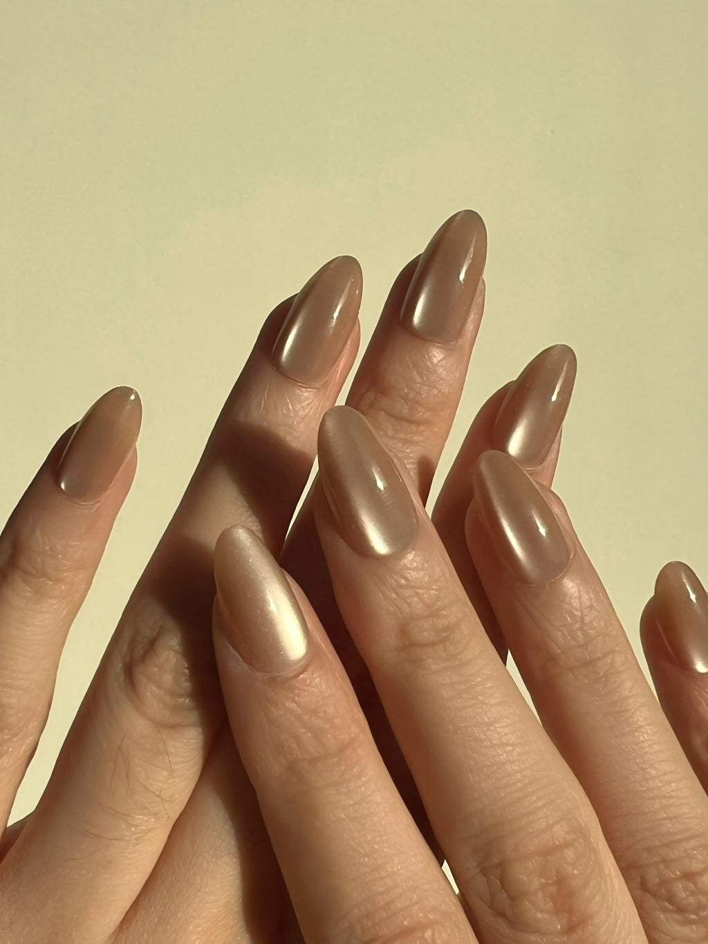 Close-up of hands look with LuxeCharm Sandstone Glow Cat-Eye Short Almond Nails on a plain background