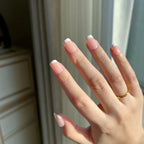 Hand with  LuxeTip French extra short square nails in pink color and a gold ring against a neutral background