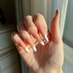 Hand with LuxeTip French long coffin press on nails in light brown color, in front of a neutral background