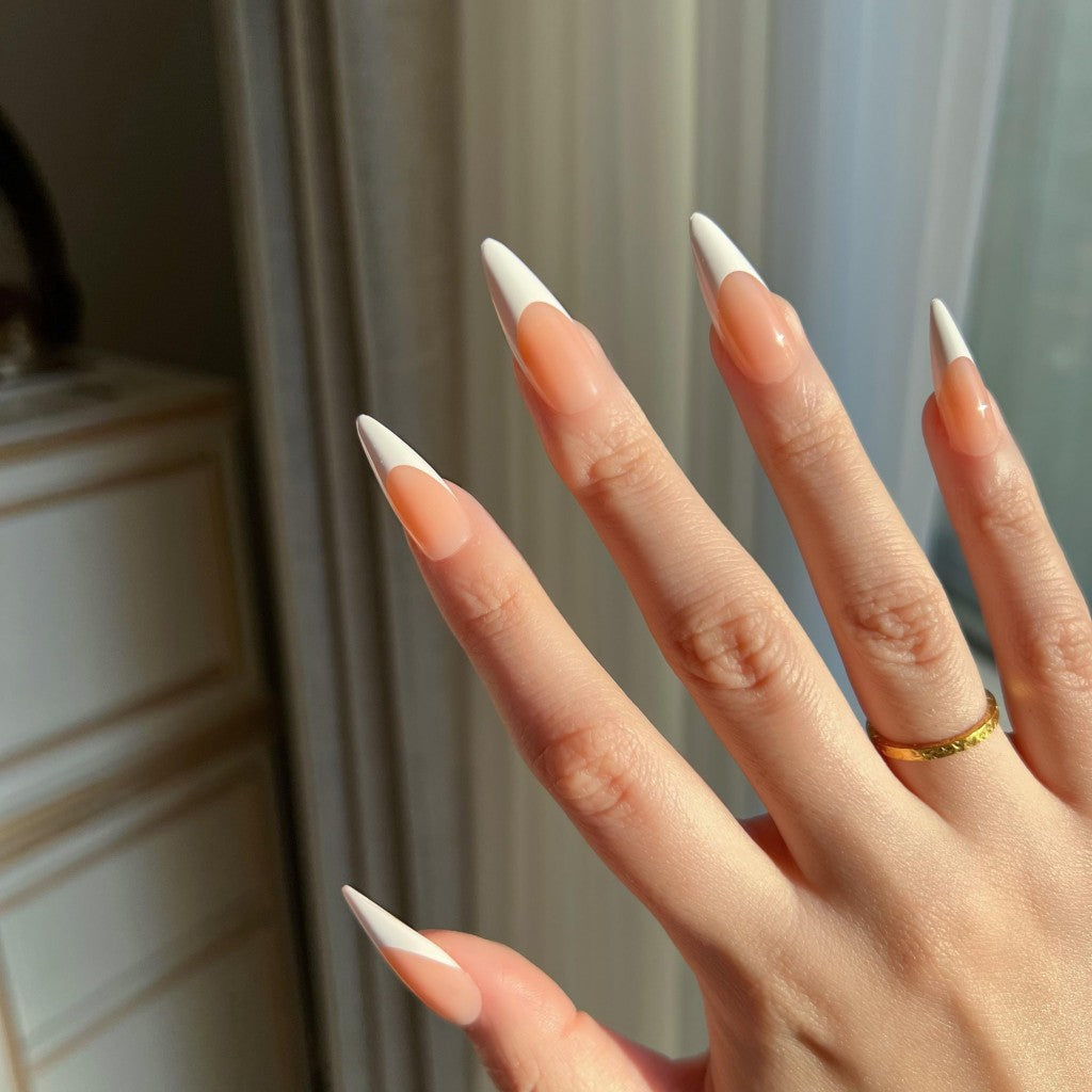 Hand with LuxeTip French long stiletto press on nails in light brown color, wearing a gold ring.