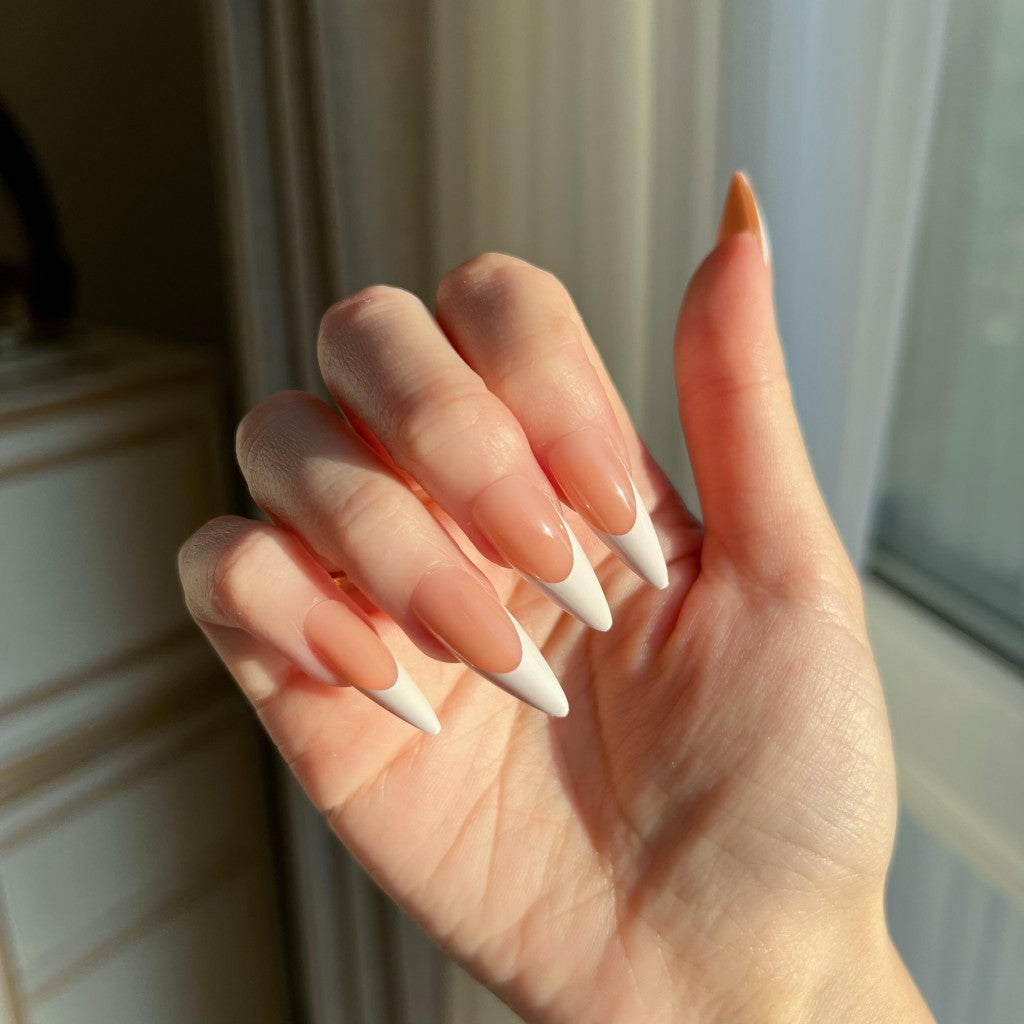 Hand with LuxeTip French long stiletto press on nails in light brown color, in front of a window.