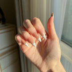 Hand with LuxeTip French long stiletto press on nails in mocha color, in a neutral setting