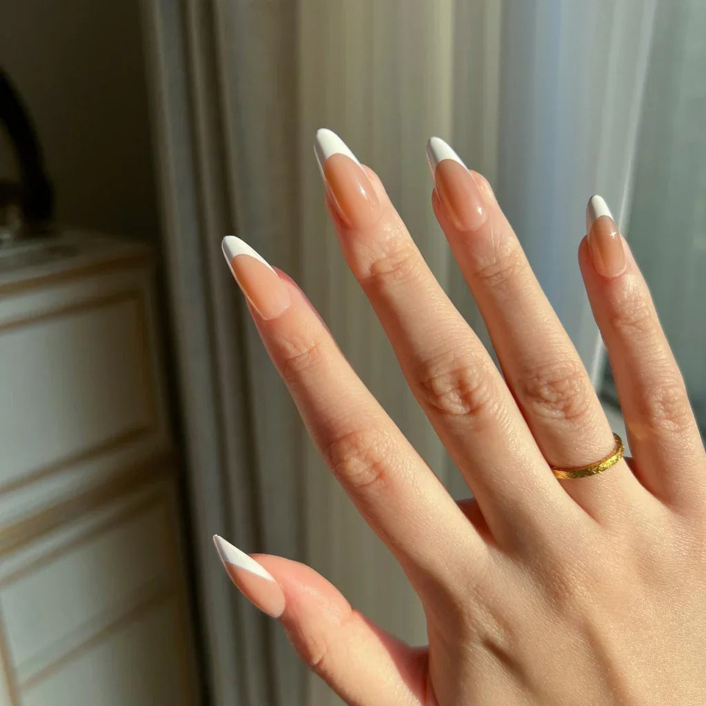 Hand with LuxeTip French medium almond press-on nails in mocha color featuring a minimalistic design, wearing a gold ring.