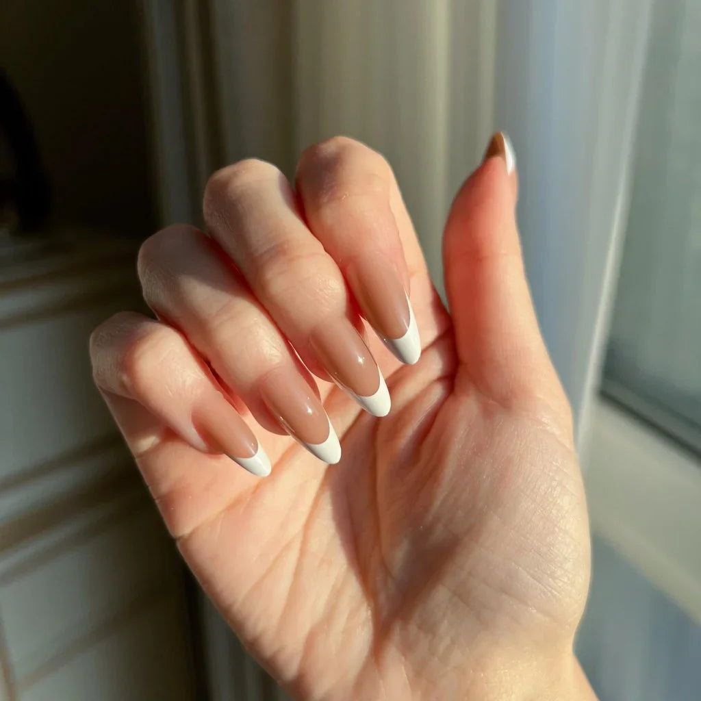 Close-up of a hand with LuxeTip French medium almond press-on nails in mocha color in a neutral setting