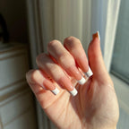 Hand with LuxeTip French medium square press on nails in light brown color, in front of a window
