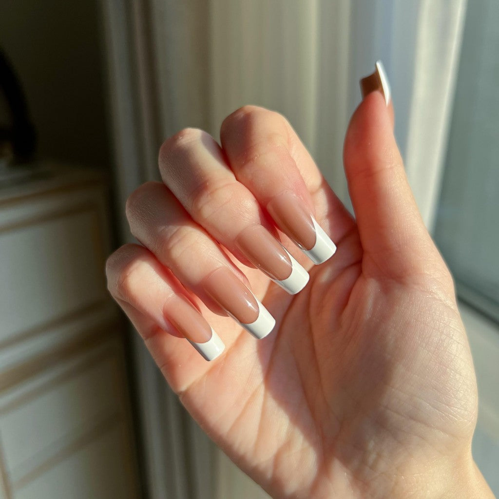 Hand with  LuxeTip French medium square press on nails in mocha color, in front of a window
