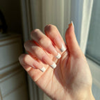 Hand with LuxeTip French medium square press on nails in peach color, in front of a window.