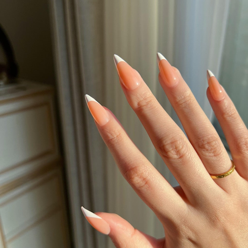 Hand with LuxeTip French medium stiletto press on nails in light brown color , wearing a gold ring.