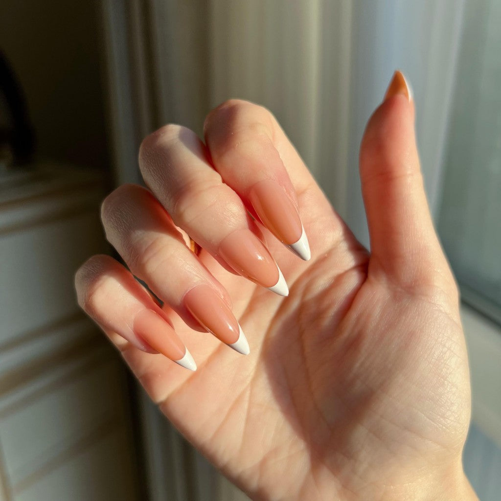 Hand withLuxeTip French medium stiletto press on nails in light brown color against a neutral background