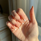 Hand withLuxeTip French medium stiletto press on nails in light brown color against a neutral background