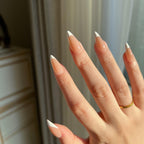 Hand with LuxeTip French medium stiletto press on nails in mocha color against a neutral background.