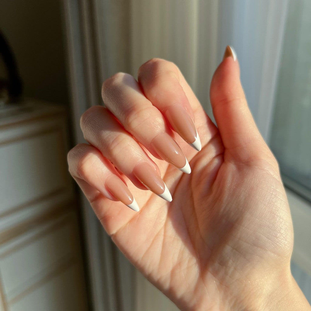 Hand with LuxeTip French medium stiletto press on nails in mocha color against a neutral background