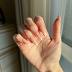 Hand withLuxeTip French medium stiletto press on nails in peach color in a neutral setting