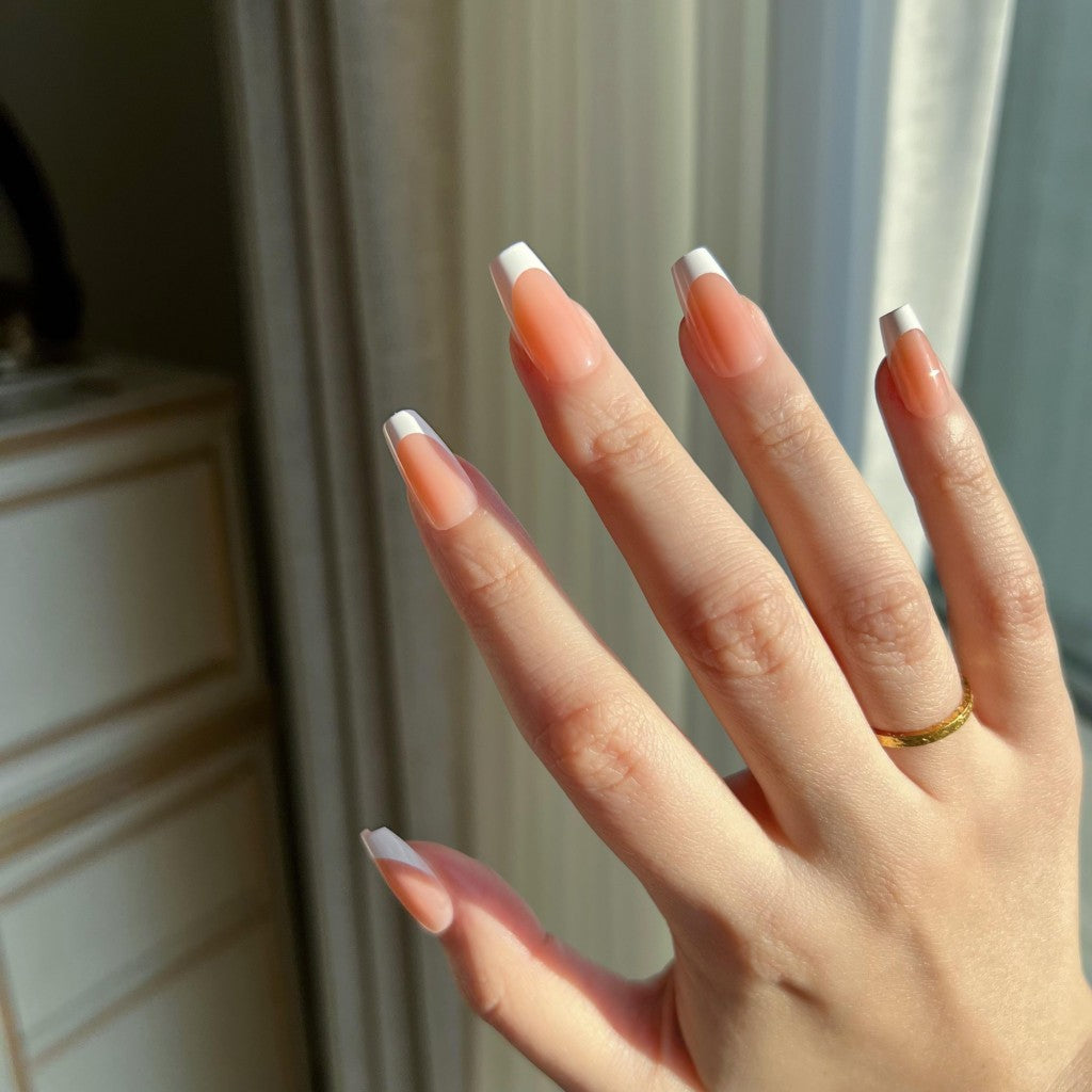 Hand with LuxeTip French short coffin press on nails in light brown color showing a gradient from light brown to white tip, wearing a gold ring.