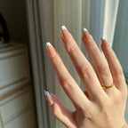 Hand with LuxeTip French short coffin press-on nails in mocha color featuring a white tip design, wearing a gold ring, against a neutral background.