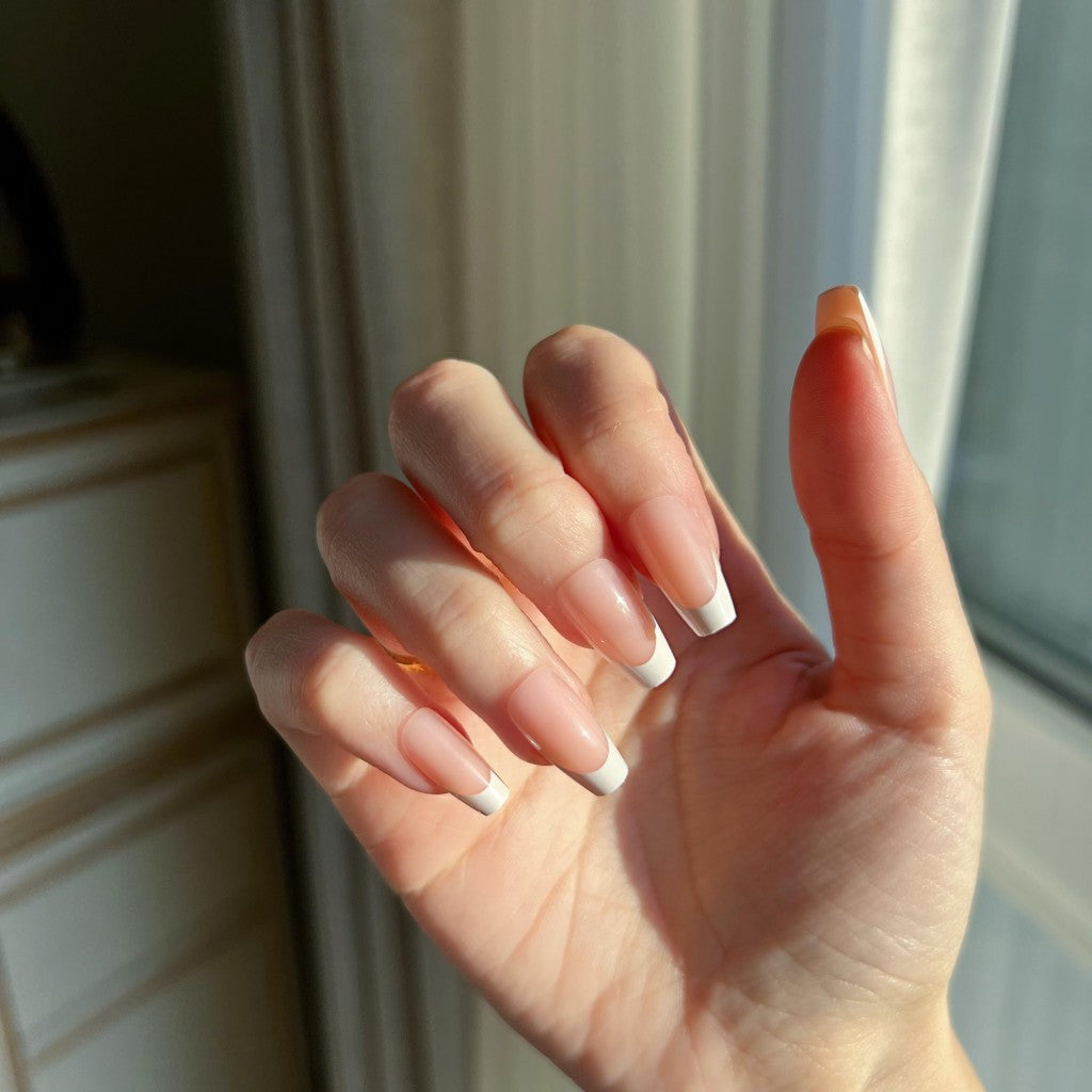 Hand with LuxeTip French short coffin press on nails in peach color, in a neutral color scheme.