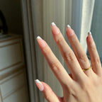 Close-up of a hand with LuxeTip French short coffin press on nails in pink color against a neutral background
