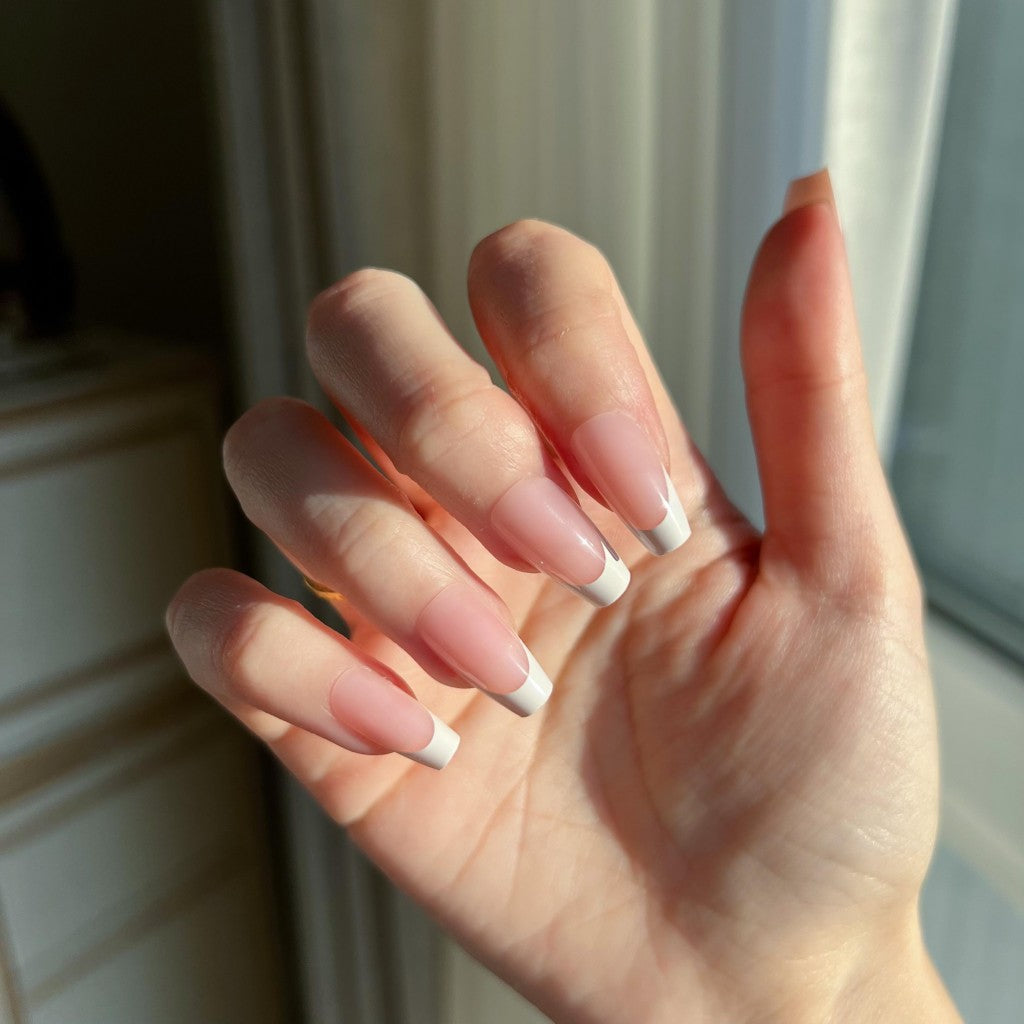 Hand with LuxeTip French short coffin press on nails in pink color, in a neutral setting