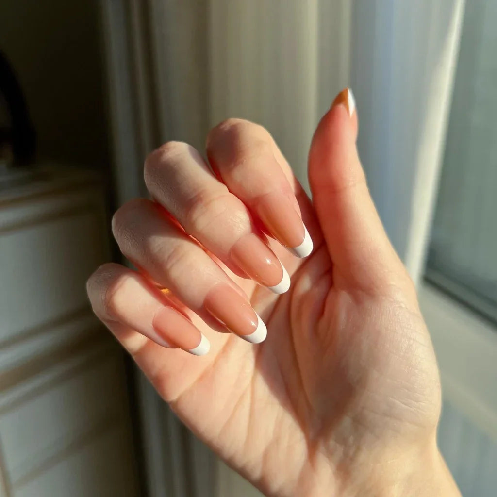 Hand with LuxeTip French short oval press-on nails with light brown color in a neutral setting