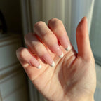 Hand with LuxeTip French short oval nails with pink color in a neutral setting