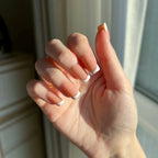 Hand with LuxeTip French short square press-on nails in light brown color in a neutral setting