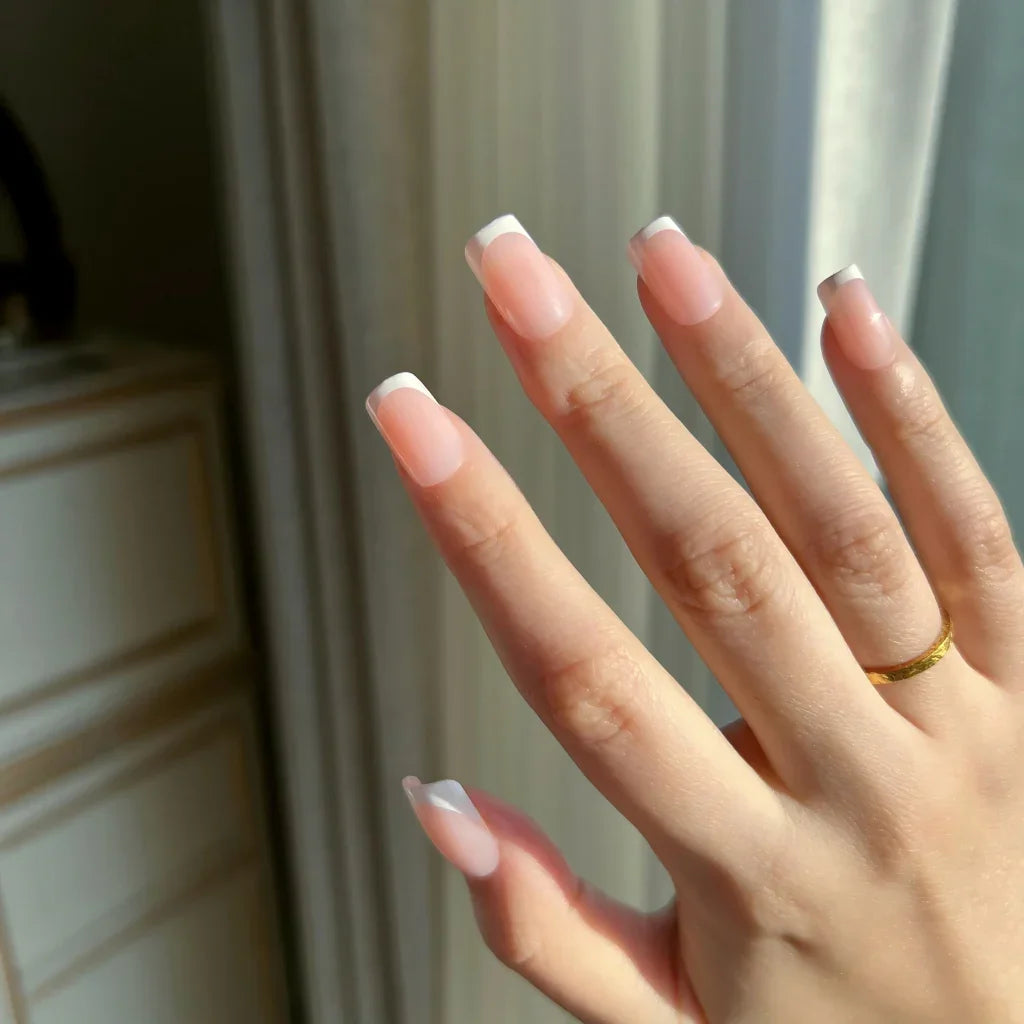 Close-up of a hand with LuxeTip French short square press-on nails in pink color in a neutral setting