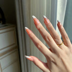 Close-up of hands wearing LuxeCharm LuxeTip glazed French Medium Almond press on nails in Light Brown color. 