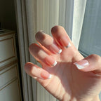 Hand withLuxeTip Glazed French short square nails with peach color in front of a window with curtains