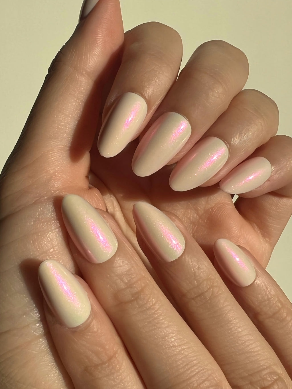 Hand with LuxeCharm Opal Haze Aurora Short Almond Nails on a neutral background