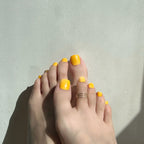 Close-up of feet with yellow press on toenails on a light background. LuxeCharm toenails