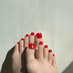 Close-up of toes with red toenails on a light gray background. LuxeCharm toenails