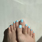 Close-up of feet with light blue press on toenails on a neutral background. LuxeCharm toenails