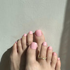Feet with pink press on toenails on toes against a light gray background. LuxeCharm Toenails