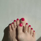 Feet with red fuchsia press on toenails on toes against a light background. LuxeCharm toenails