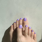 toes with purple press on toenail on a light gray background