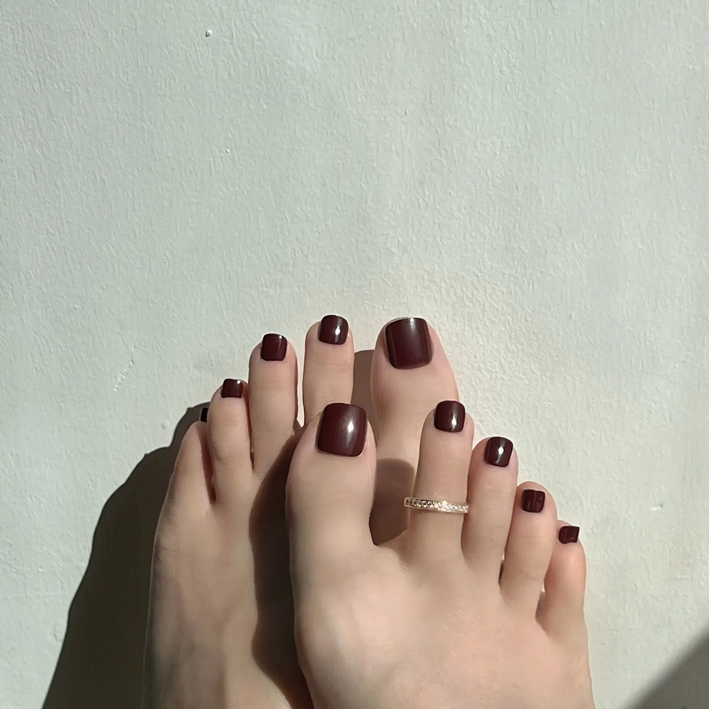 Close-up of toes with dark mocha press on toenails on a light background. LuxeCharm toenails