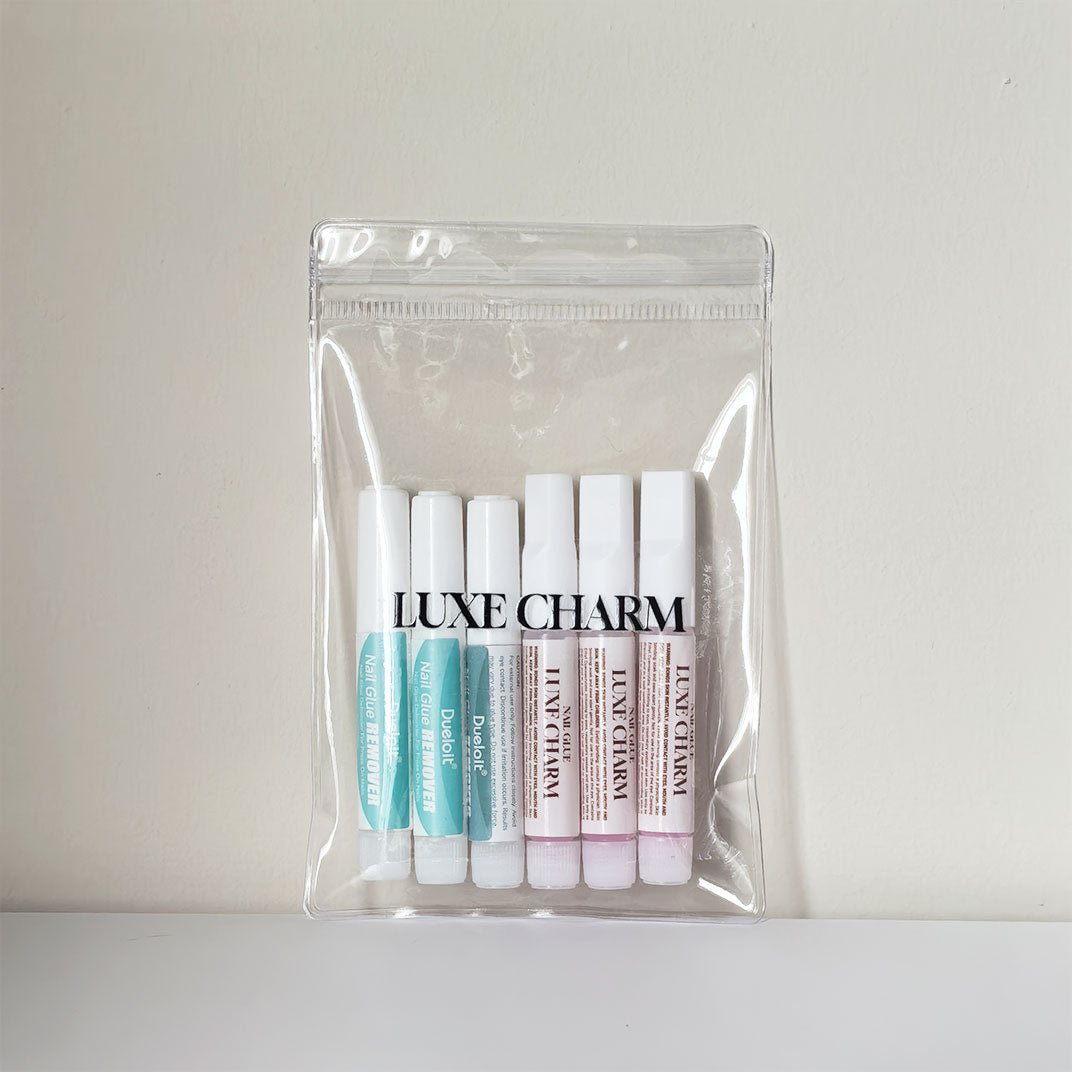Pack of Luxe Charm nail glue and nail remover in a clear plastic bag on a light gray background